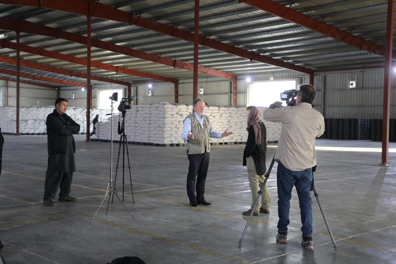 David Beasley, United Nations World Food Programme Executive Director (centre), being interviewed by PBS correspondent Jane Ferguson at a WFP food warehouse in Kabul. © WFP/Arete/Sadeq Naseri