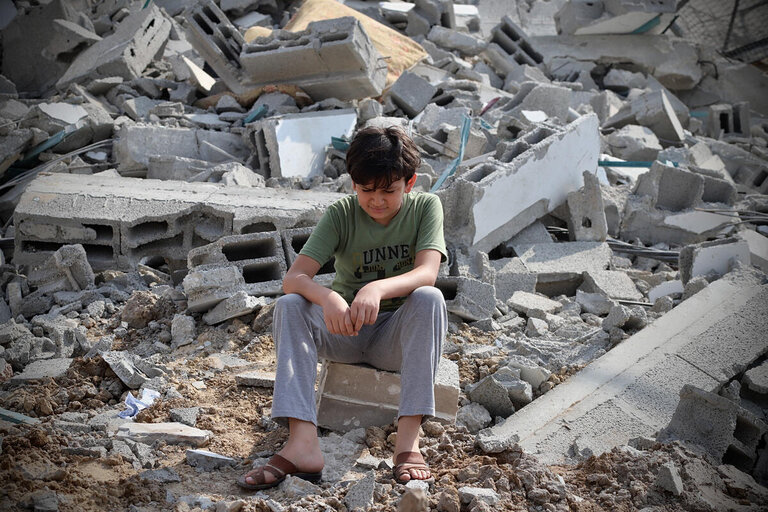 En pojke bredvid ruinerna av en byggnad i Gaza som träffats av en raket.