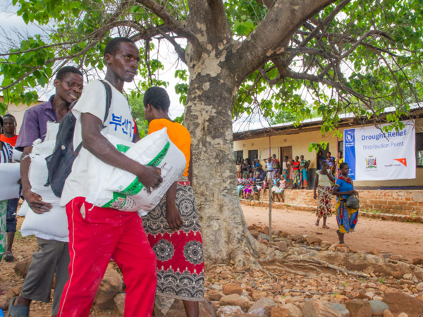 Människor tar emot majsmjöl och bönor vid en livsmedelsutdelningspunkt I Gwembe – WFP Zambia. Bild: WFP/ Paul Mboshya Jr