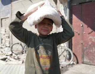 Syrien, Aleppo. Barn går med sina föräldrar i kön, eller skickas för att hämta bröd ensamma innan de går till skolan. Foto: WFP/Hussam Al Saleh 