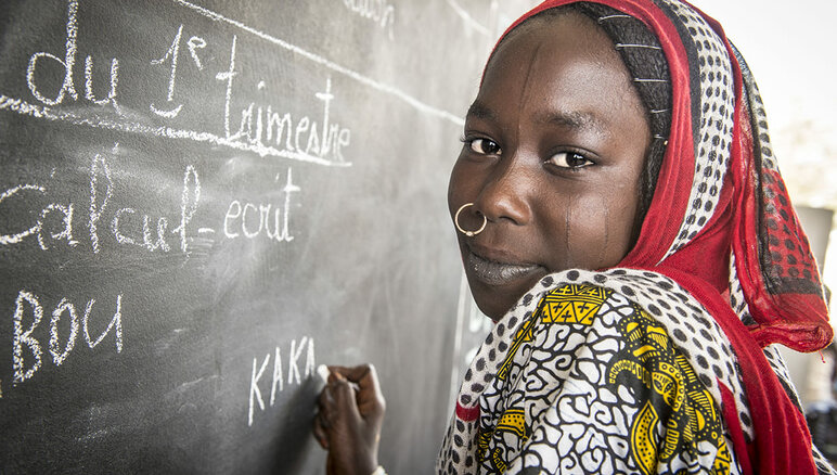 Kaka Marabou skriver sitt namn på skolans svarta tavla i Yakoua, vid Tchadsjön. Flyktingar, fördrivna människor och andra fattiga samhällen vid Tchadsjön är beroende av humanitärt bistånd för att överleva och tillgången till grundläggande utbildning är också begränsad. WFP/Giulio d'Adamo